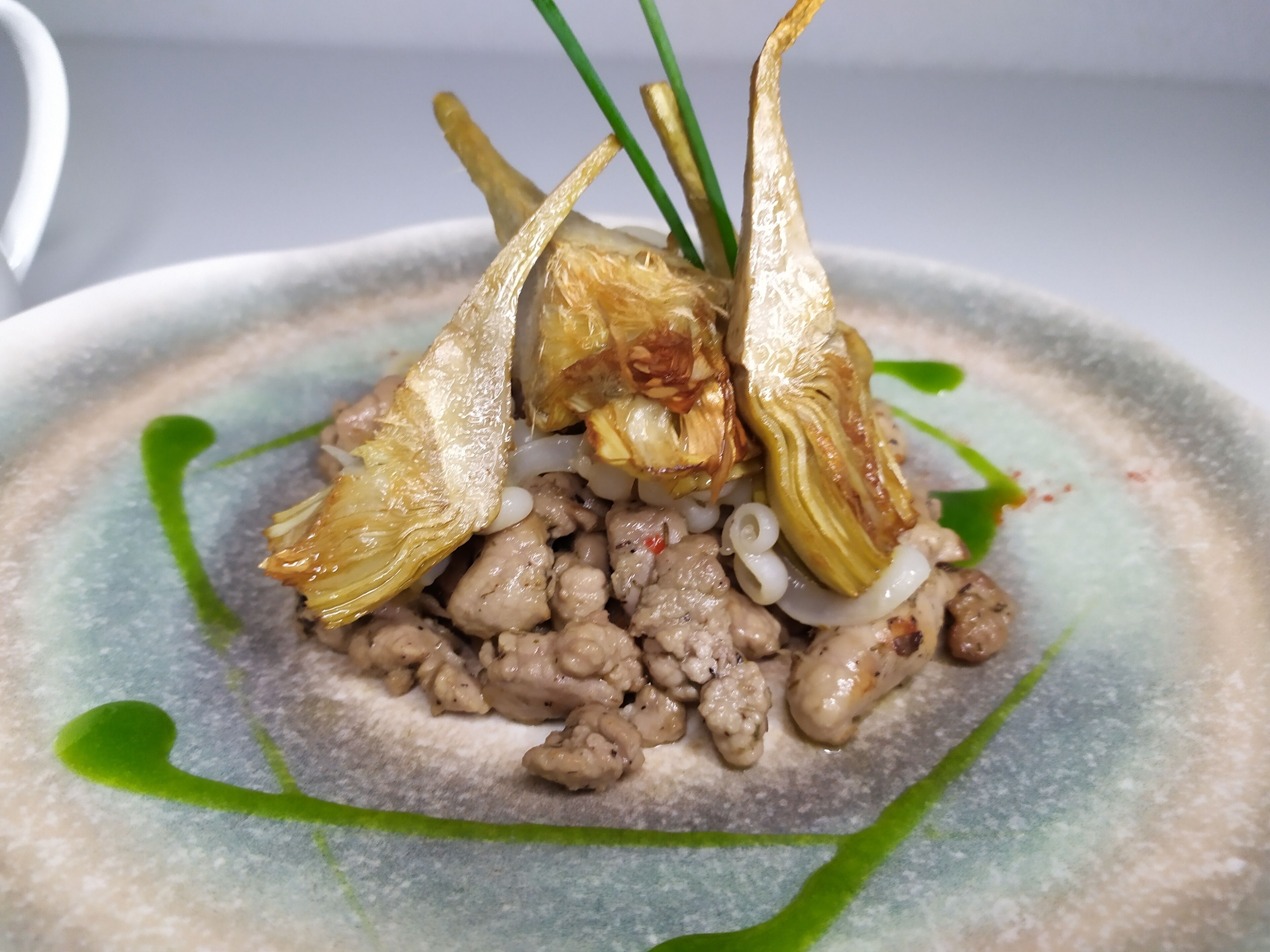 Un plato con alcachofas, salchicha y cebollas.