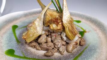 Un plato con alcachofas, salchicha y cebollas.