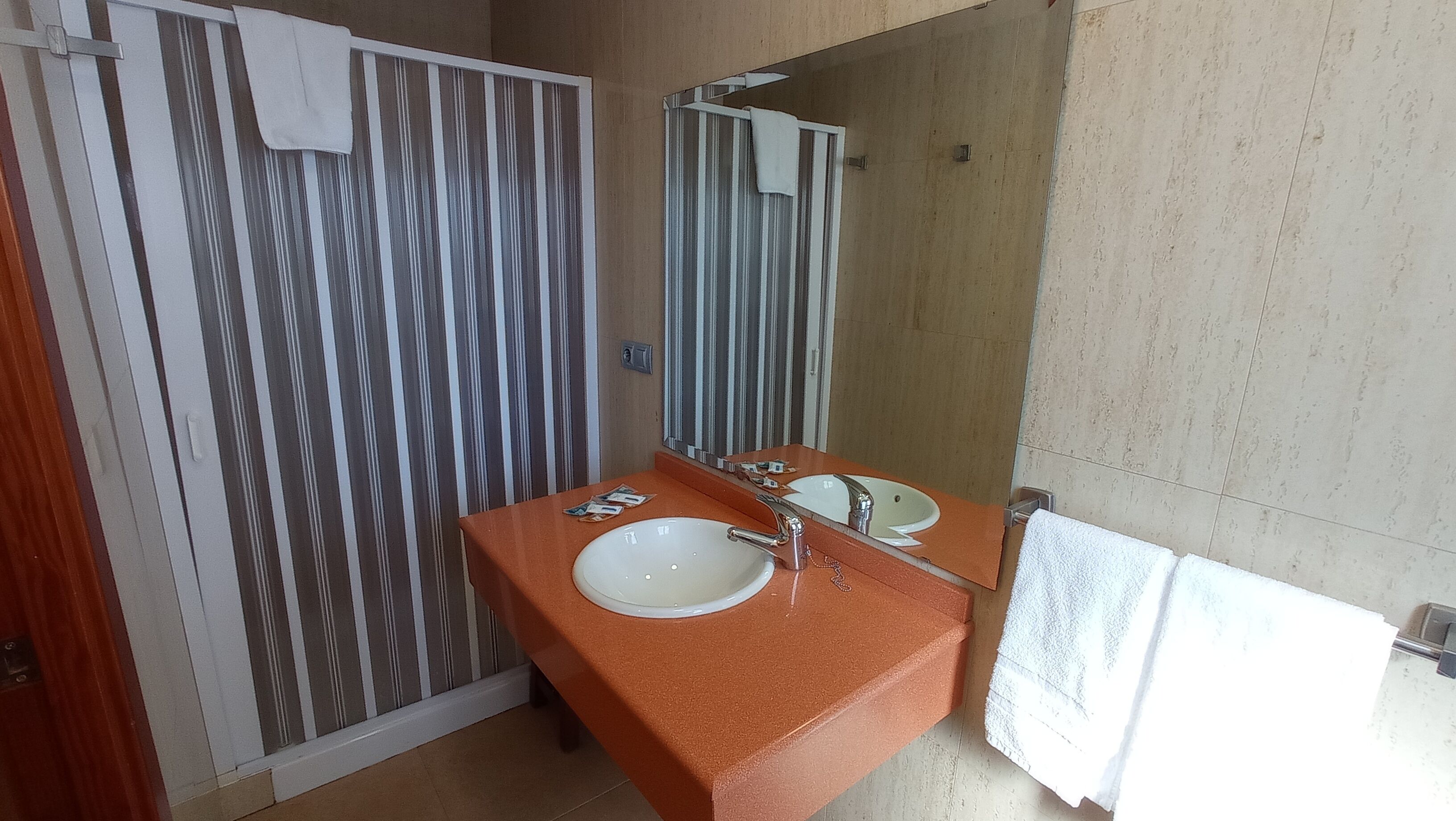 A bathroom with a shower, two sinks, and a mirror.