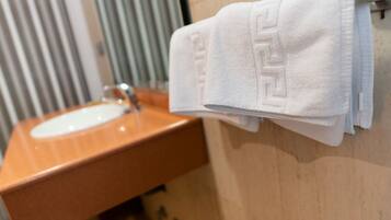 A bathroom with a wooden vanity, a white sink, and a towel hanging on a rack.