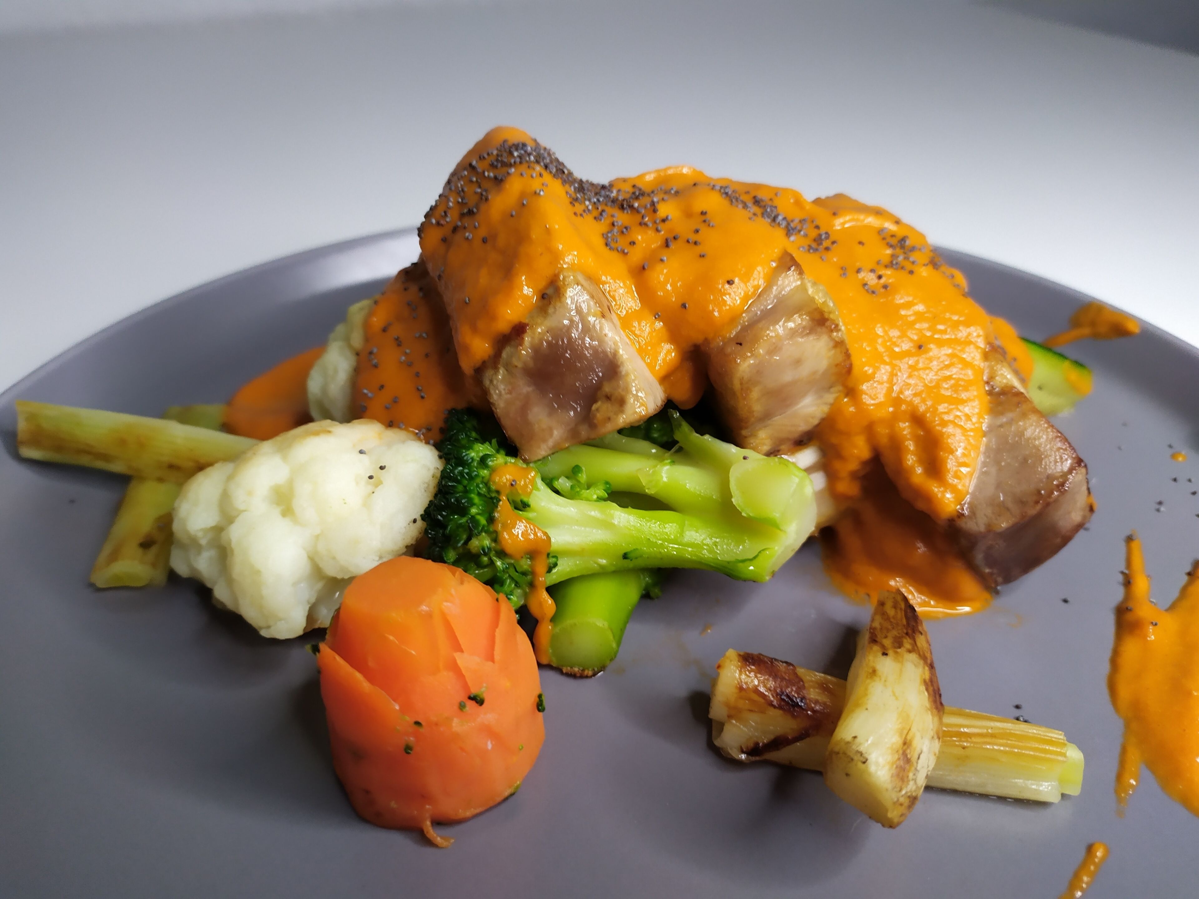 A plate of food with meat, vegetables, and sauce.