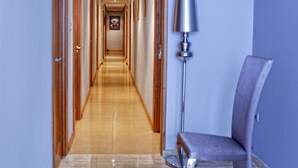 A hotel hallway with wooden doors, a marble floor, a modern lamp, and a chair. - Pensión Restaurante Casablanca (Torreperogil)