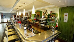 A bar area with a long counter, multiple chairs, and a variety of bar tools and bottles. - Pensión Restaurante Casablanca (Torreperogil)