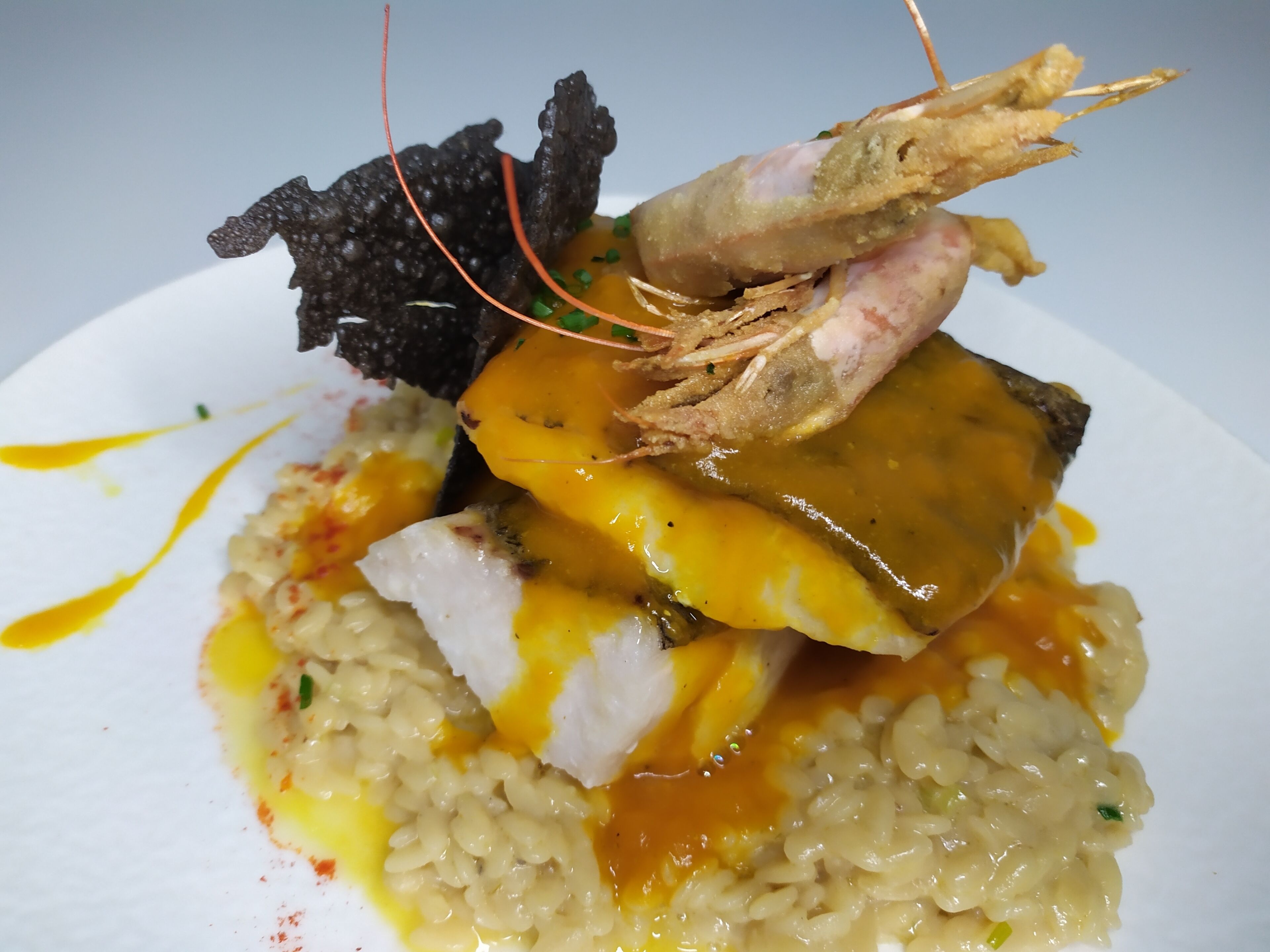 A plate of food with rice, a piece of fish, and a shrimp.