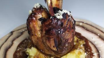 A plate with a grilled meat and mashed potatoes topped with a creamy sauce.