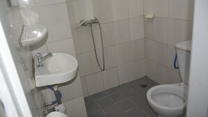 A small bathroom with a white sink, a toilet, and a shower. - Résidence Hotel Carmel (Abidjan)
