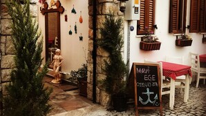 Una entrada de hotel encantadora con fachada de piedra, un letrero y una pizarra con el menú.