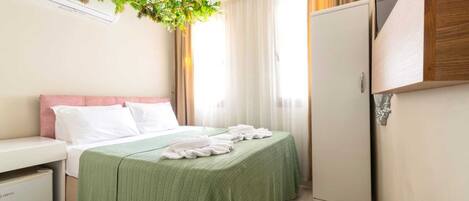 Habitación de hotel con cama, escritorio, armario y una planta colgante.