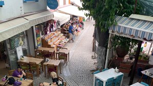 Calle adoquinada con mesas al aire libre y una exhibición de comida.