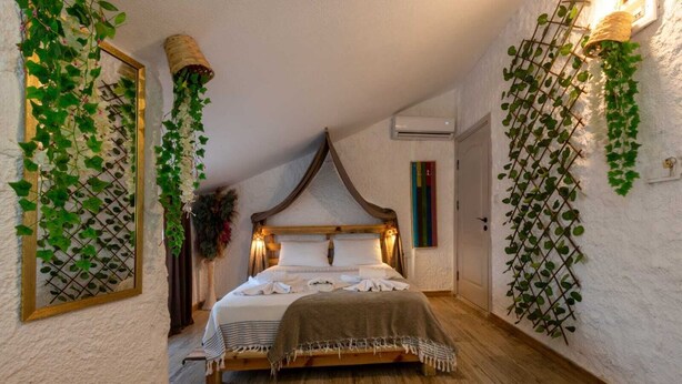 Un dormitorio con cama de madera, paredes blancas y decoración con hiedra verde.