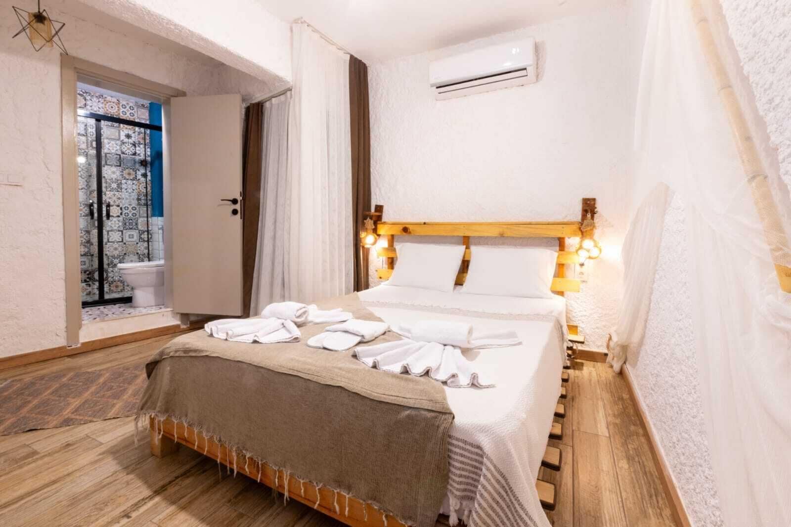 Een hotelkamer met een bed, een badkamer met douche en een airconditioning aan de muur.
