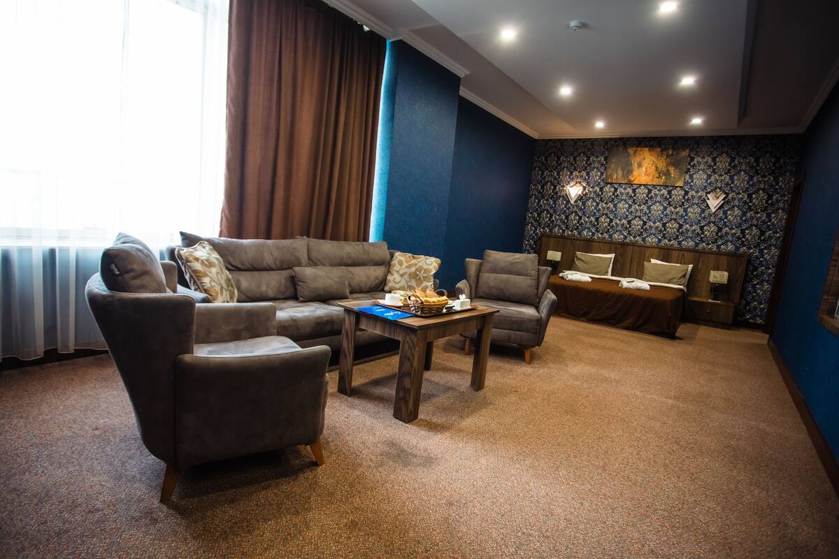 A modern living room with a sectional sofa, armchairs, a coffee table, and a small dining table.