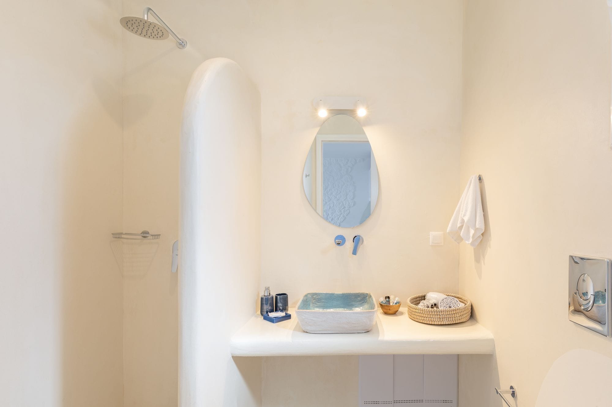 A bathroom with a shower, a sink with a mirror, and a towel hanging on the wall.