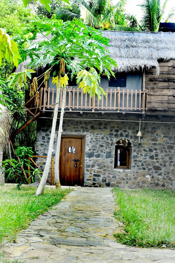 A rustic stone building with a thatched roof, a wooden door, and a small window.