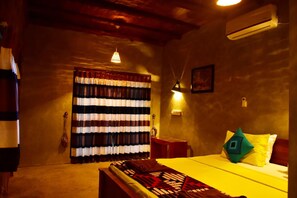A cozy room with a bed, a small table, a hanging lamp, and a window with striped curtains.