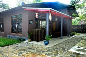 A modern house with a covered porch, stone pathway, and potted plants.