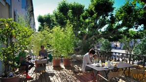 Un patio al aire libre con piso de madera, plantas en macetas y sillas de metal.