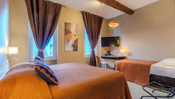 A hotel room with two beds, a desk, a TV, and a window with curtains.