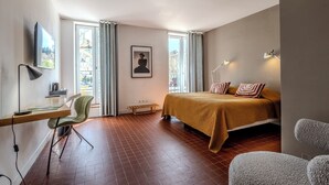 Un dormitorio moderno con cama, escritorio, silla y ventana con cortinas.
