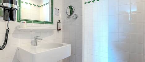 A bathroom with a white sink, a mirror, a hairdryer, and a shower.