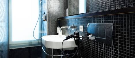 A modern bathroom with a white sink, a handheld showerhead, and a mirror.