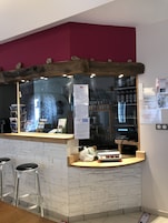 Uma área de bar com balcão de pedra, banquetas e um quadro de cardápio.