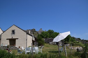 Uma casa rústica com escadaria de pedra, área de estar externa e vista para colinas rochosas.