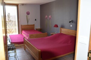 A bedroom with two wooden beds, a small table, a chair, and a red lamp.