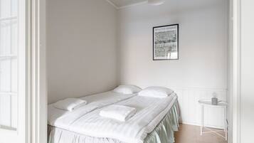 A bedroom with a large bed, a small table, and a framed picture on the wall.
