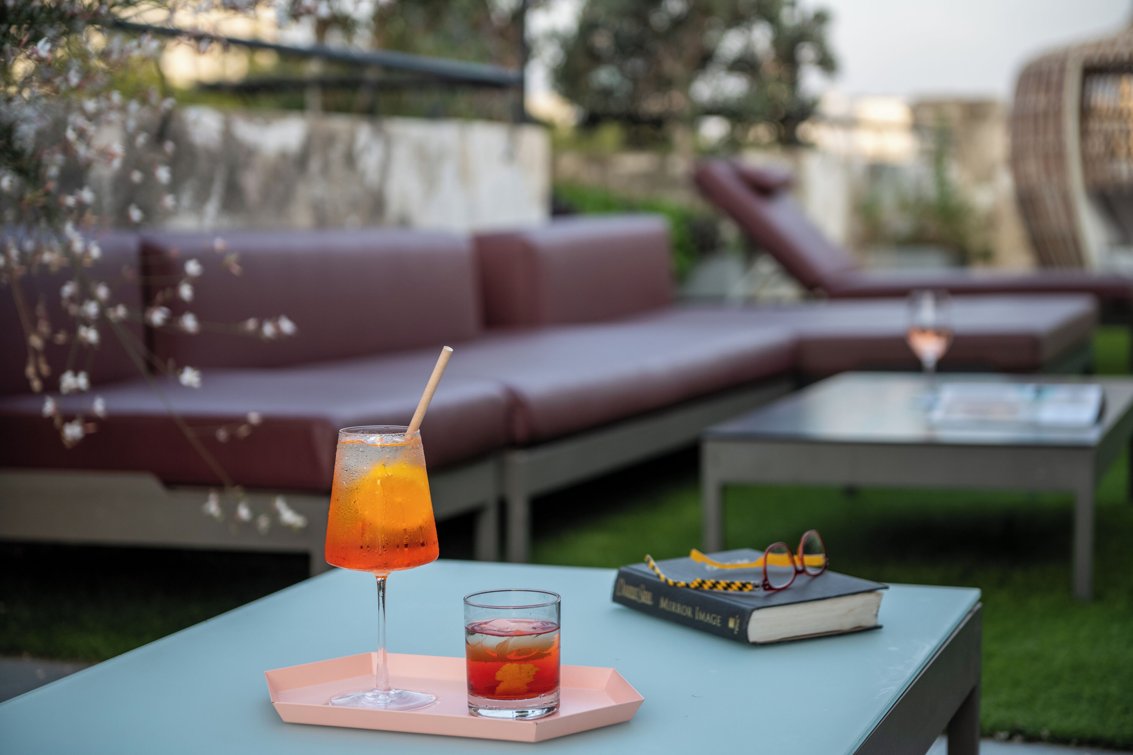 A patio with a table, a drink, a book, and a sofa.