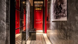 A hallway with a red door, a bench, and a patterned floor. - Assemblage Boutique (Tel Aviv)