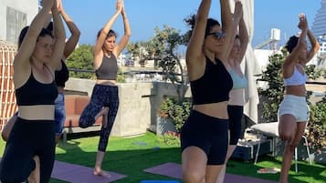 A group of people performing yoga on outdoor mats under a canopy.