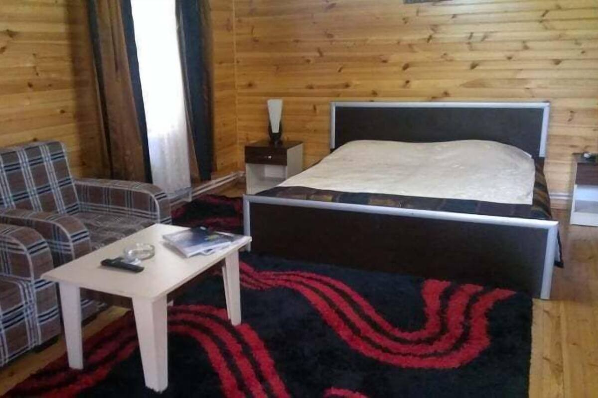 A wooden-paneled room with a bed, a sofa, and a small table.