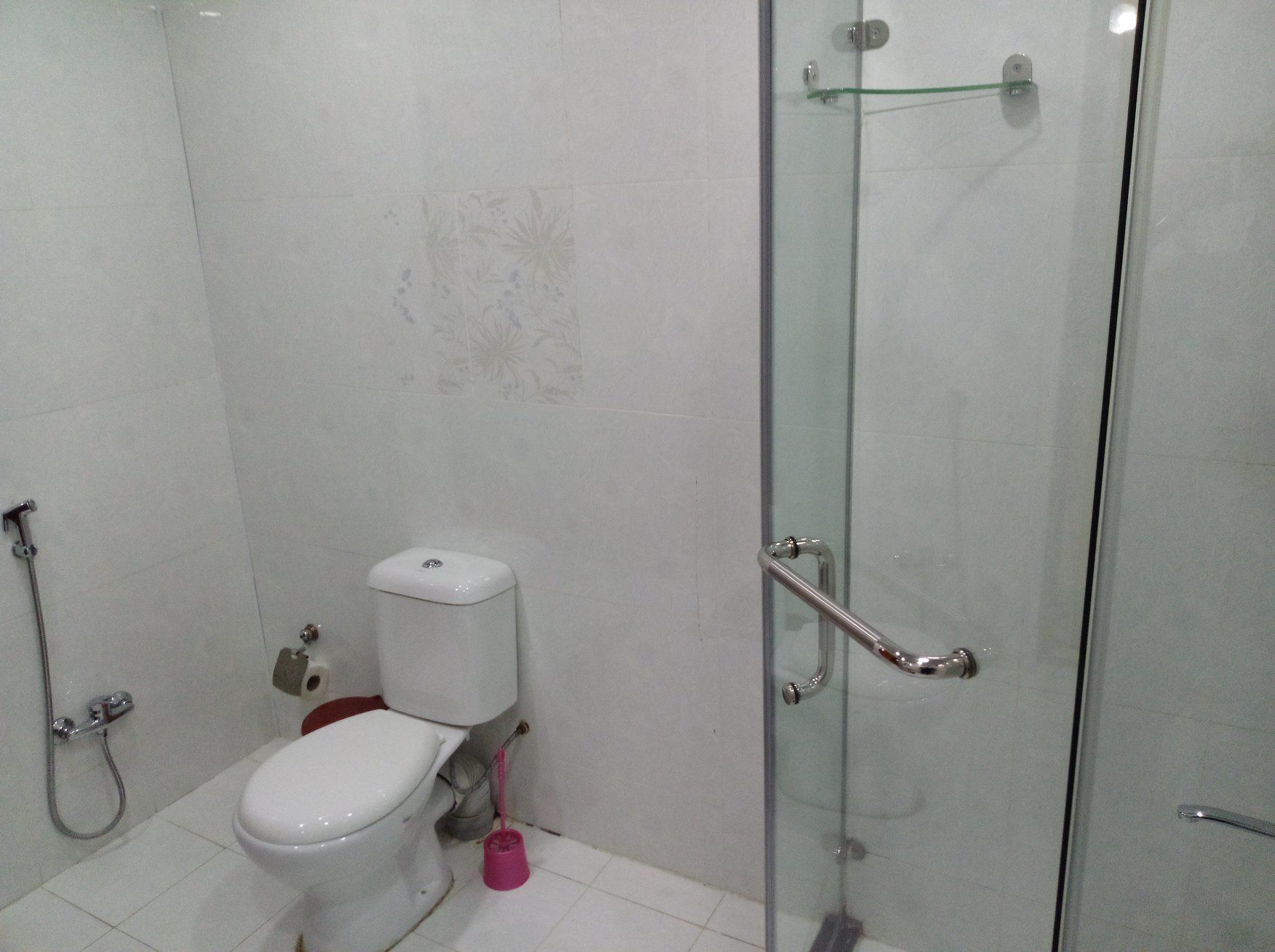 A bathroom with a toilet, a shower, and a glass shower door.