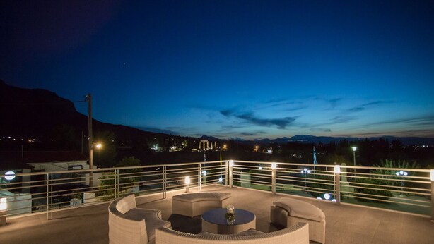 A rooftop terrace with outdoor seating and a view of distant mountains. - Olympus (Corinth)