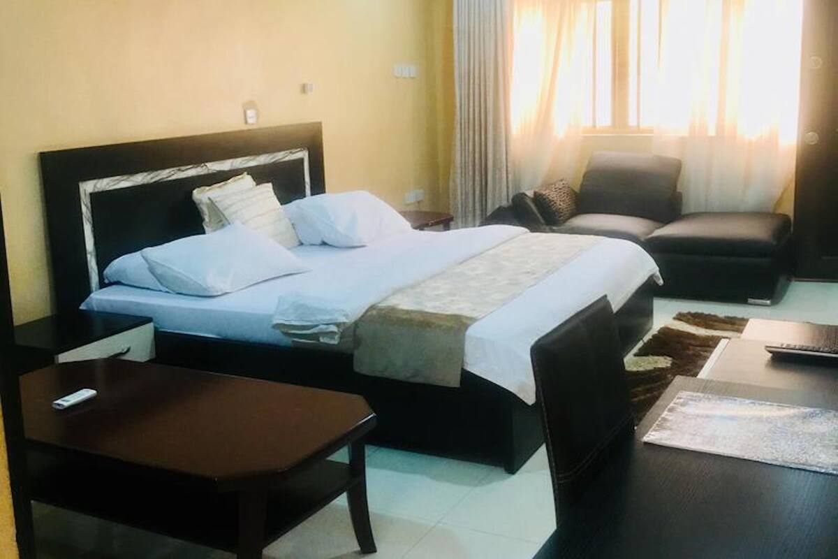A hotel room with a bed, a desk, a chair, and a window with curtains.