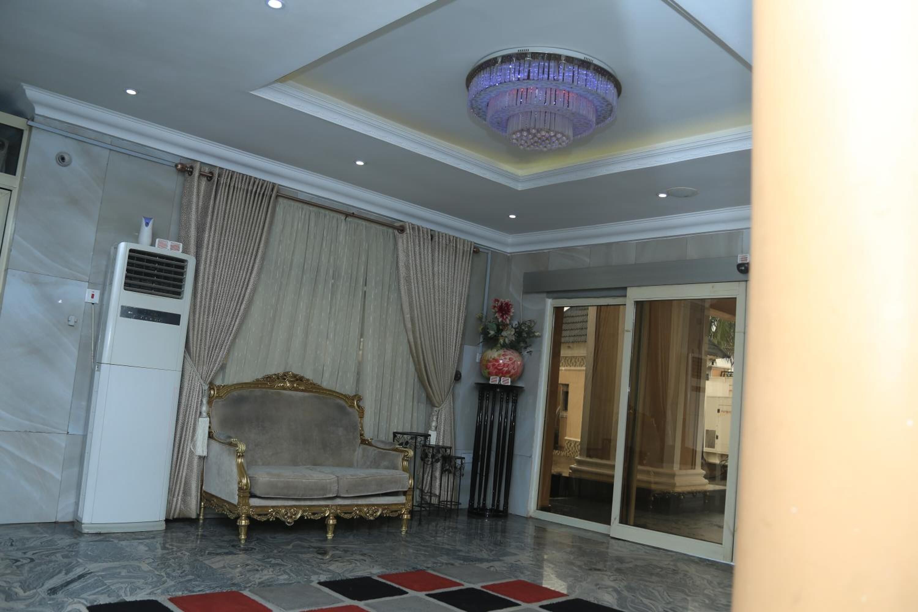 A room with a chandelier, a sofa, curtains, and a large window.