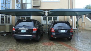 Deux SUV Toyota noirs étaient stationnés sous un grand parasol, sur une allée dallée.