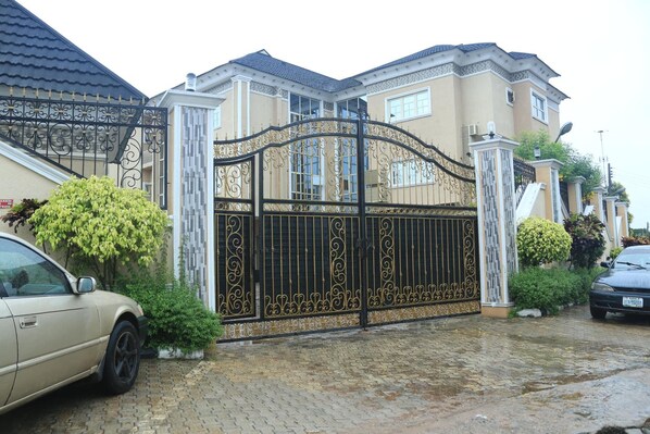 A gated residential property with a driveway, a car, and a well-maintained lawn.