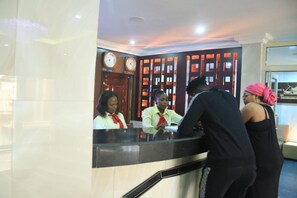 A hotel reception desk with a modern design, featuring a reception area, clocks, and a counter.