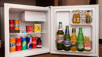 Un refrigerador abierto con diversas bebidas y aperitivos.