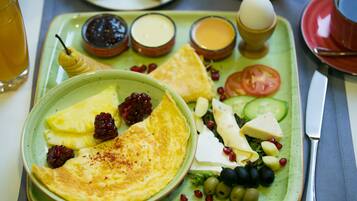 Un plato de desayuno con huevos, queso, tomates, pepinos, aceitunas y bayas.