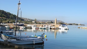 A harbor with boats docked, a stone tower, and a stone wall in the background. - Kanakaris Apartments (Xylokastro-Evrostina)