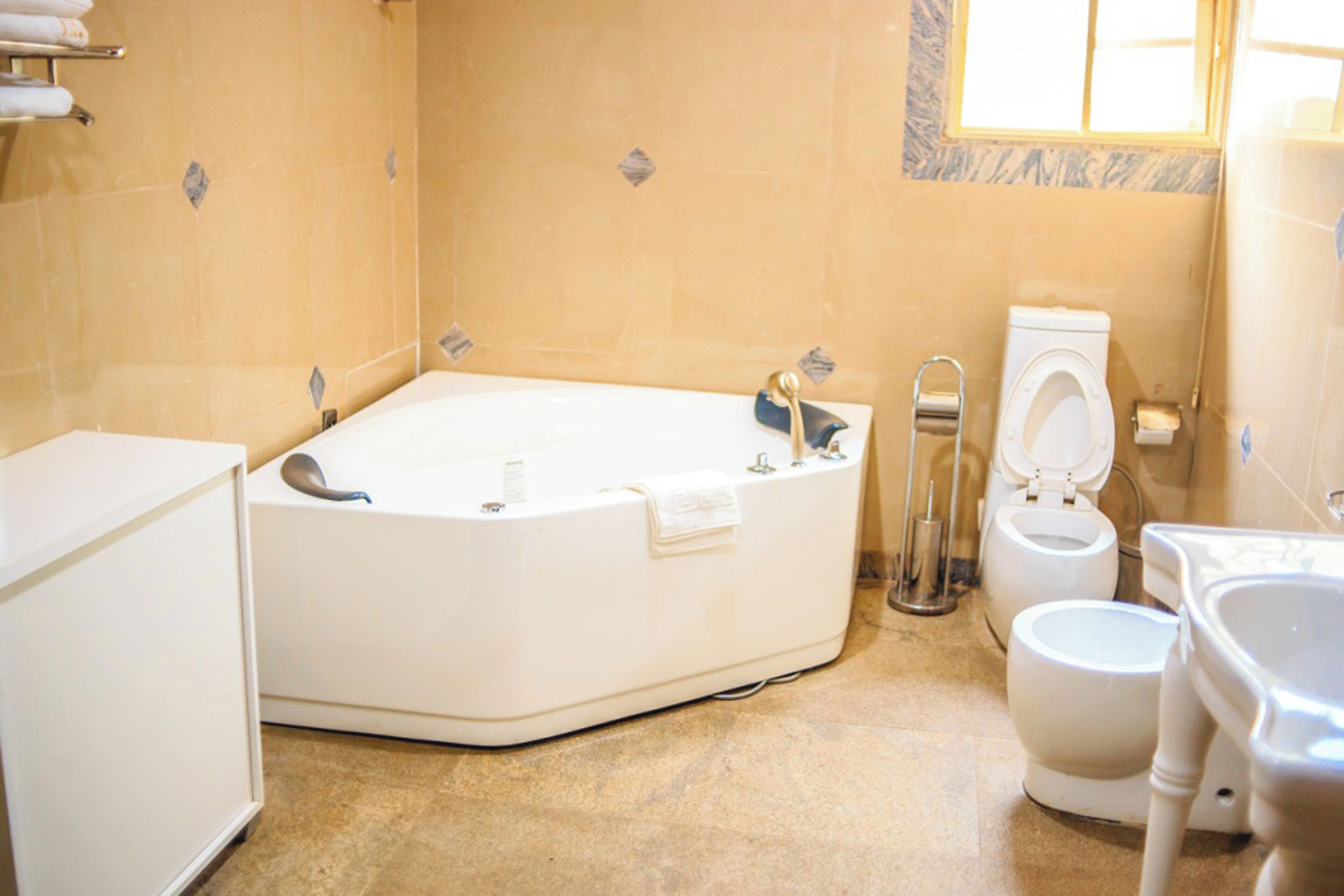 A bathroom with a bathtub, two toilets, and a sink.