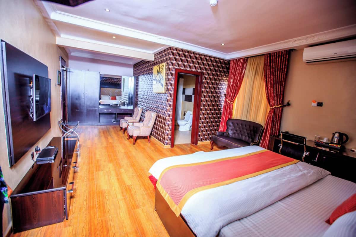Une chambre d’hôtel avec un grand lit, une télévision, un bureau avec un ordinateur et une petite kitchenette.