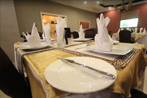 A dining table set with white plates, silverware, and folded napkins.