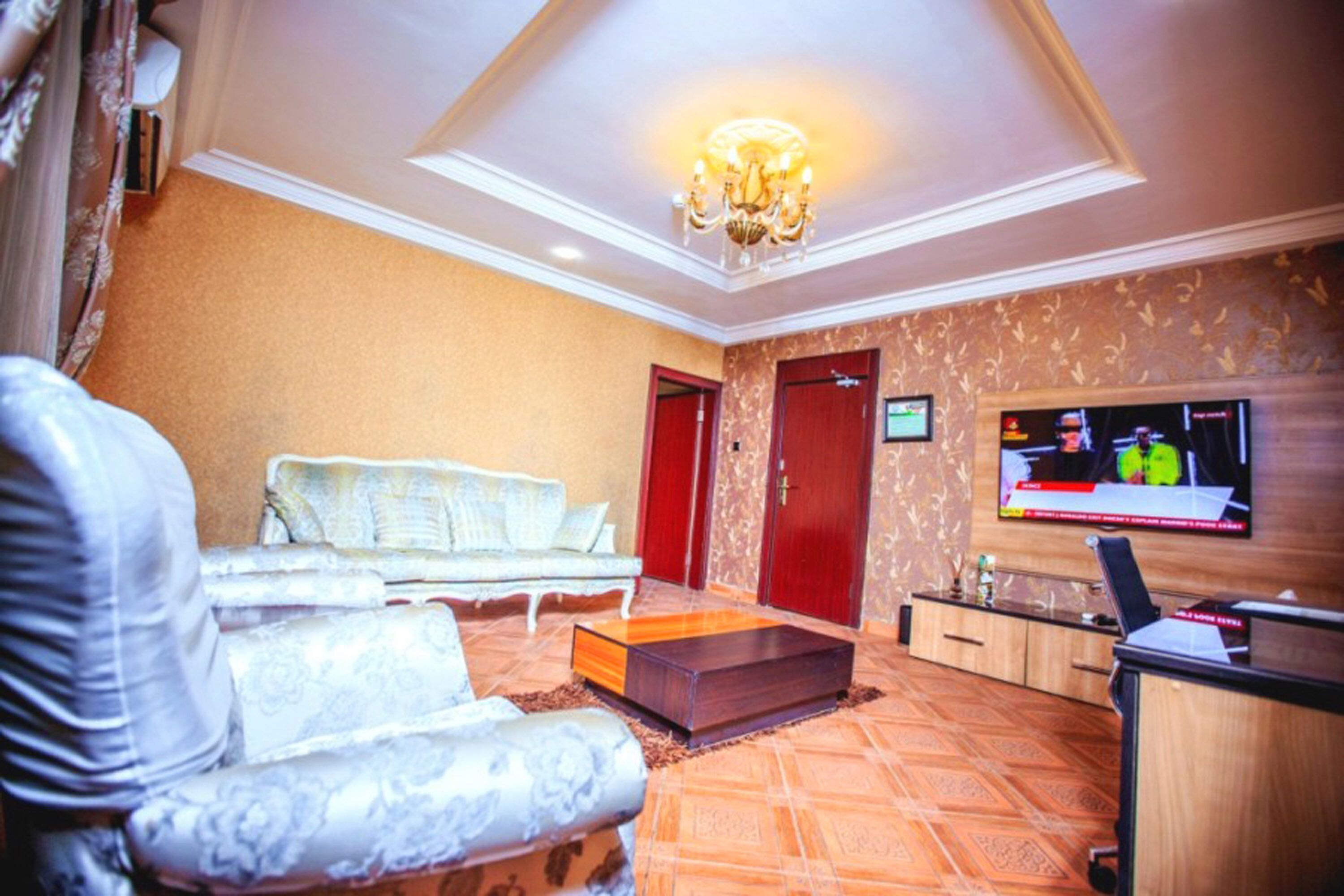 Een hotelkamer met een bank, een aan de muur bevestigde televisie en een houten kast.