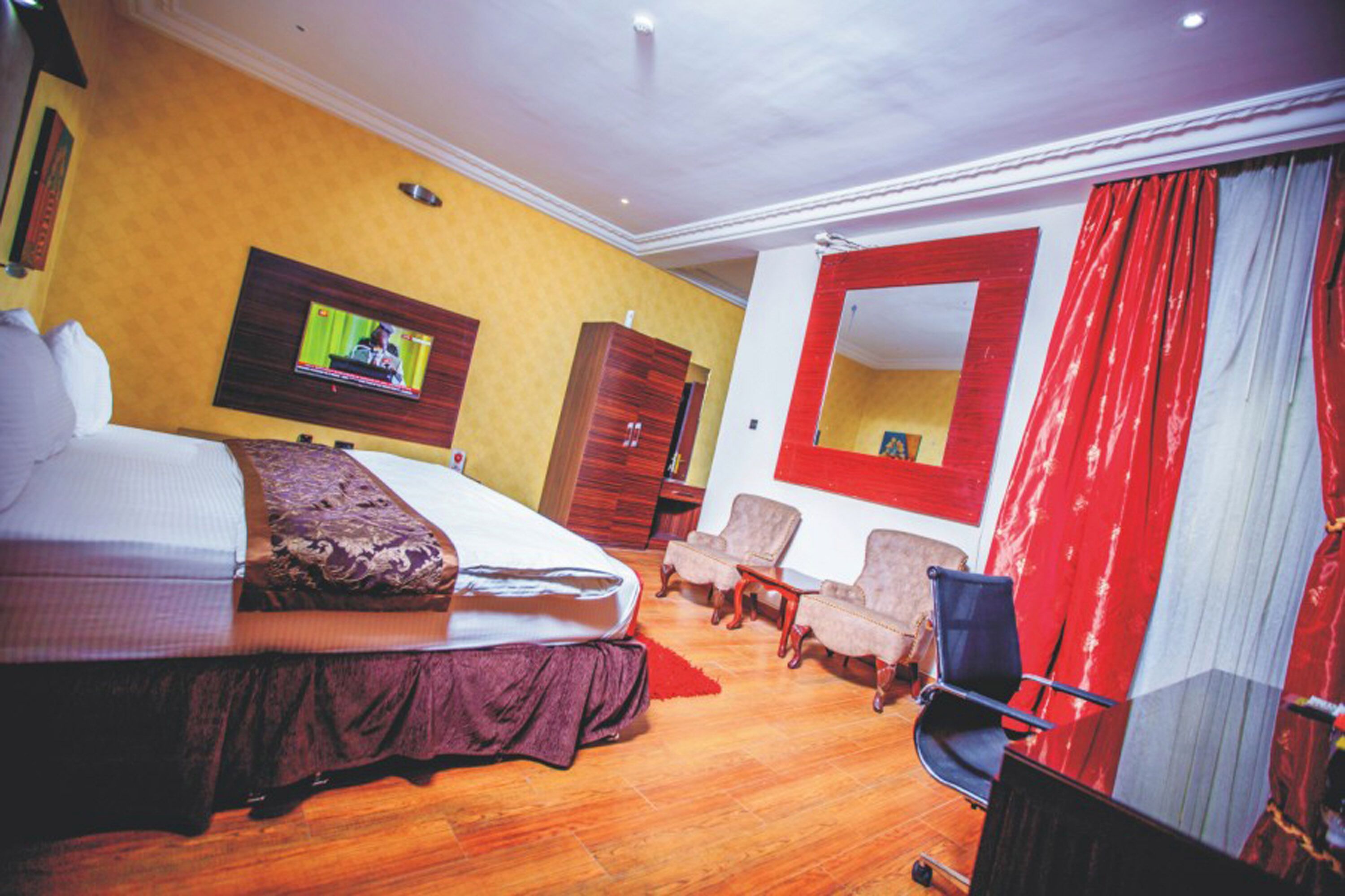 Una habitación de hotel con cama, televisor, armario, escritorio y silla.