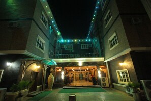 A hotel entrance with a covered walkway, potted plants, and a Christmas tree.