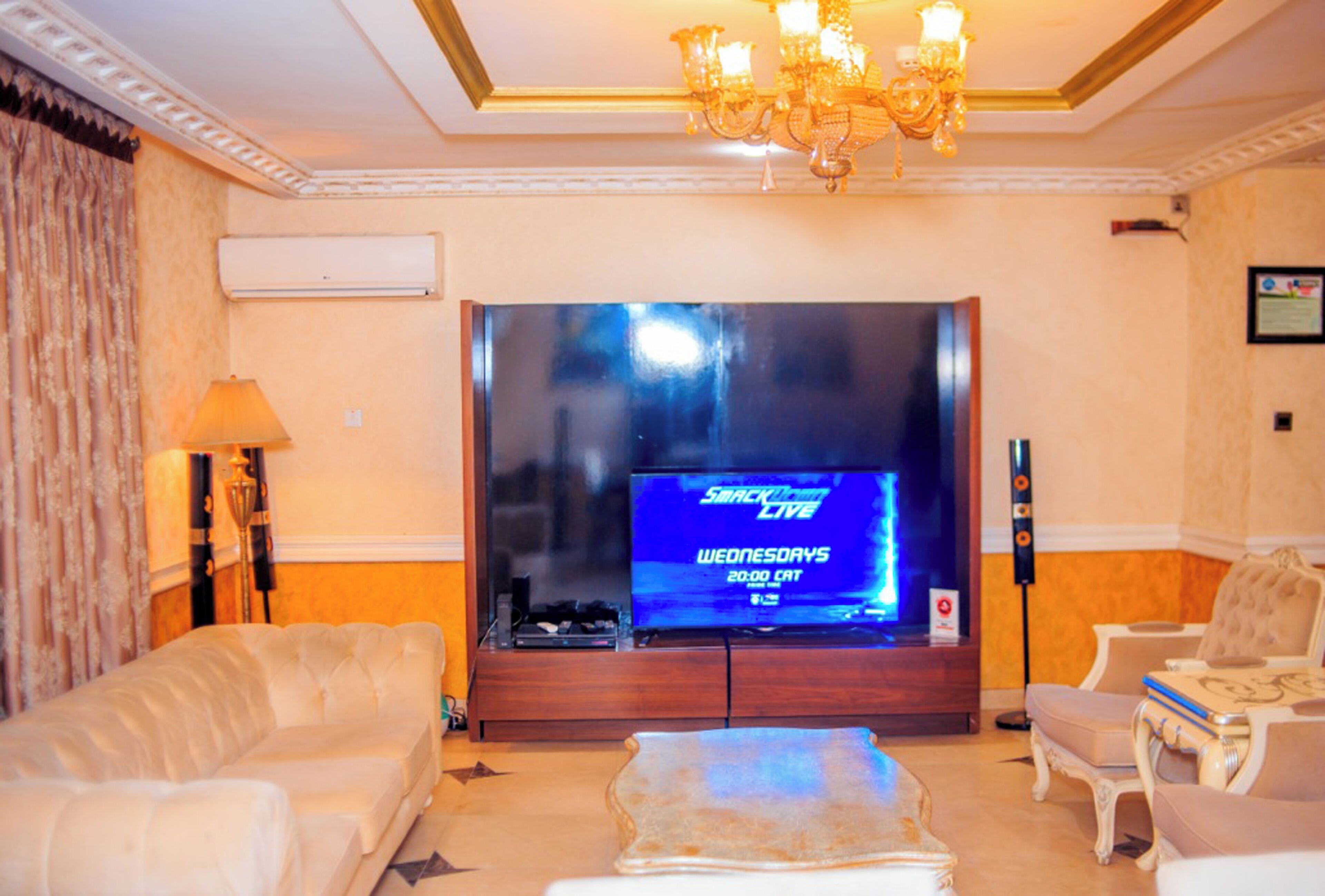 Un salón con un televisor de pantalla plana grande, una araña y un sofá.